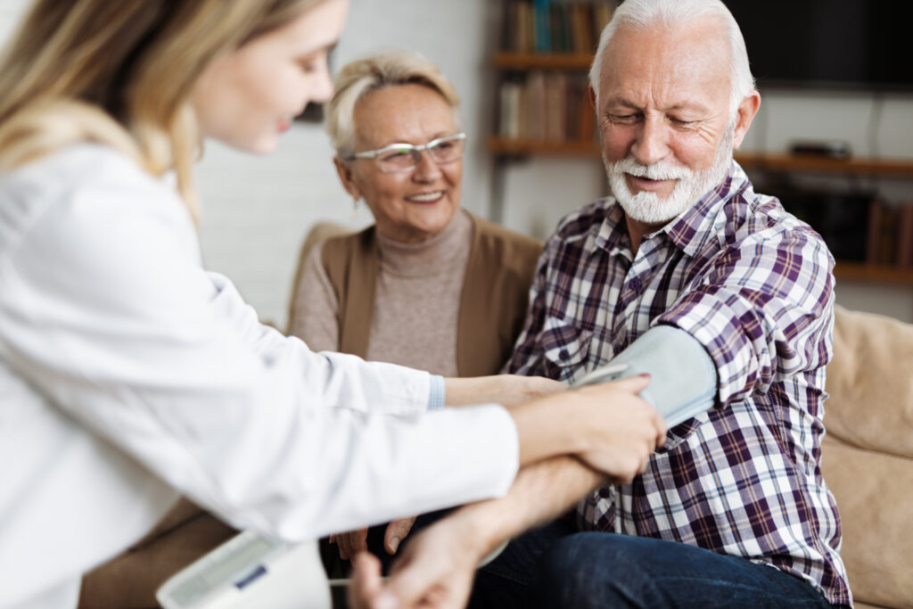 Female nurse checking blood pressure of a senior man during her home visit